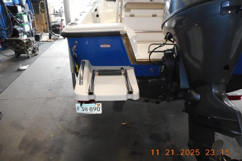 Slide: The Image of 2022 Key West 1720 Center Console boat in a garage, featuring outboard motor and swim platform. - 18