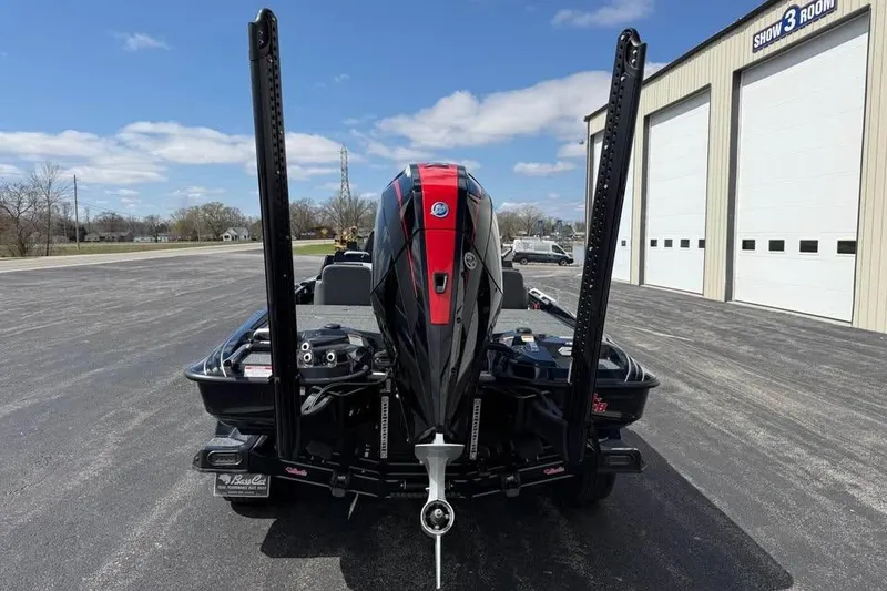 Slide: The Image of 2026 Bass Cat Jaguar STS boat with powerful outboard motor, parked near a showroom. - 2