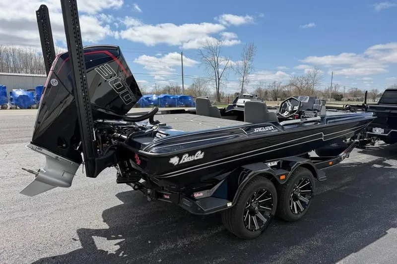 Slide: The Image of 2026 Bass Cat Jaguar STS boat on trailer, sleek black design, powerful engine, outdoor setting. - 4