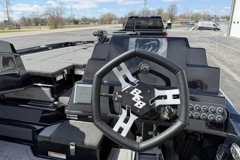 Slide: The Image of 2026 Bass Cat Jaguar STS boat dashboard with steering wheel and control panel. - 8