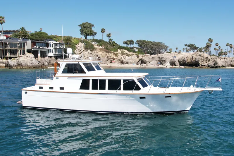 The Image of 1980 Roughwater 41 yacht cruising near rocky coastline with palm trees. - 0