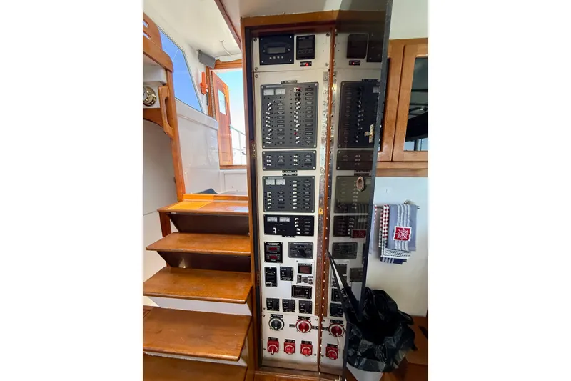 Slide: The Image of Electrical control panel on 1980 Roughwater 41 boat, near wooden stairs and nautical decor. - 16