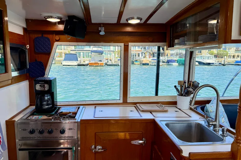Slide: The Image of Interior of 1980 Roughwater 41 boat kitchen with stove, sink, and marina view. - 23
