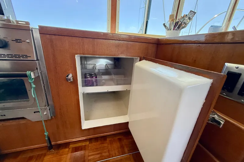 Slide: The Image of 1980 Roughwater 41 yacht interior with open fridge and wooden cabinetry. - 26