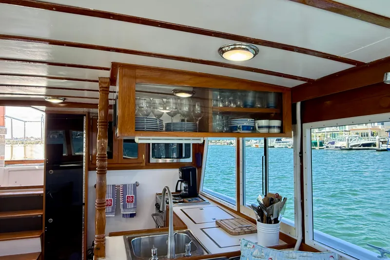 Slide: The Image of Interior of 1980 Roughwater 41 boat with kitchen, wooden cabinets, and marina view. - 28