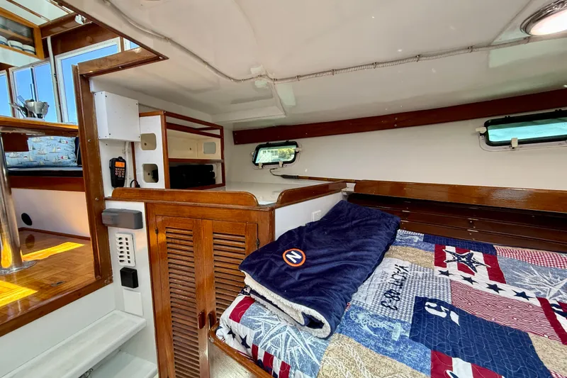 Slide: The Image of Cozy cabin interior of 1980 Roughwater 41 boat with quilted bedding and wooden accents. - 41