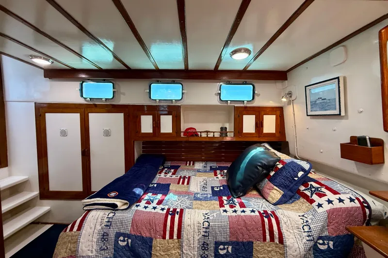 Slide: The Image of Cozy 1980 Roughwater 41 yacht cabin with nautical-themed bedding and wooden cabinetry. - 42