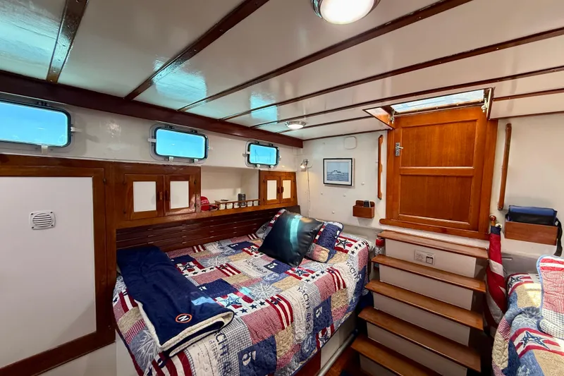 Slide: The Image of Cozy cabin interior of 1980 Roughwater 41 boat with quilted bedding and wooden accents. - 44