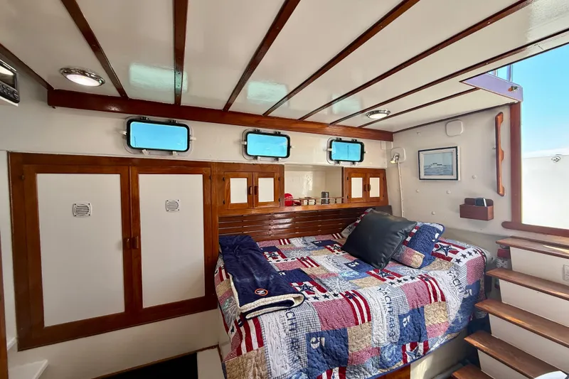 Slide: The Image of Cozy cabin interior of 1980 Roughwater 41 boat with quilted bed and wooden accents. - 47