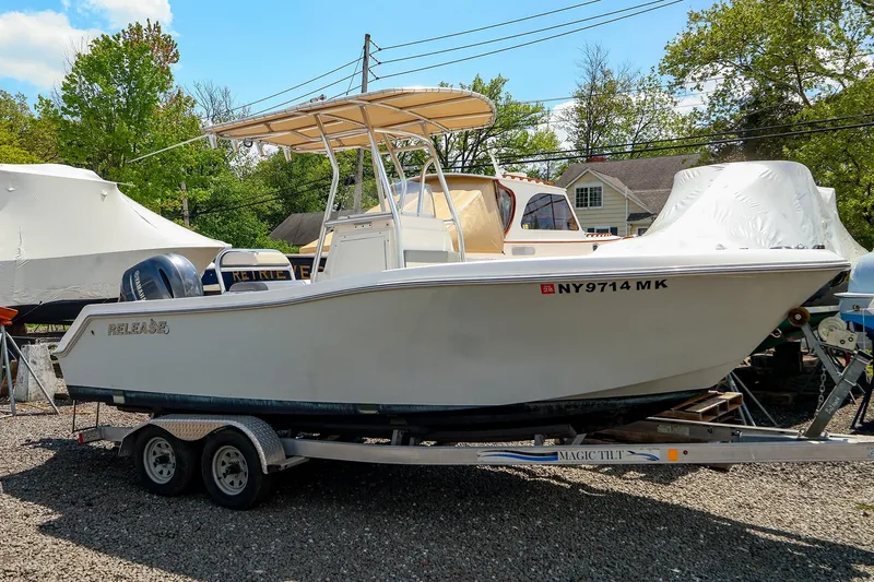 Slide: The Image of 2016 Release 208 RX boat on trailer, parked outdoors, with trees and houses in background. - 24