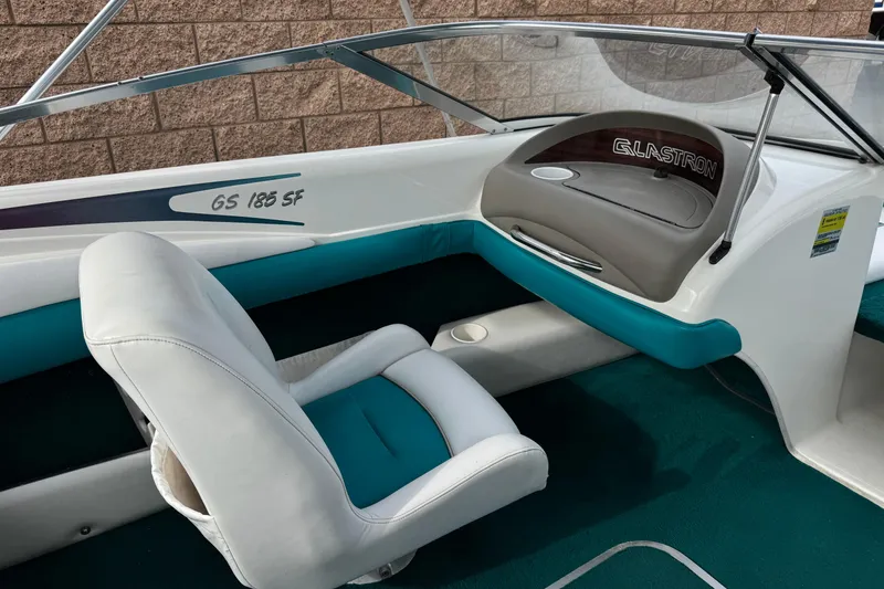 Slide: The Image of 1997 Glastron GS 185 boat interior with teal and white seating, showcasing dashboard and windshield. - 17