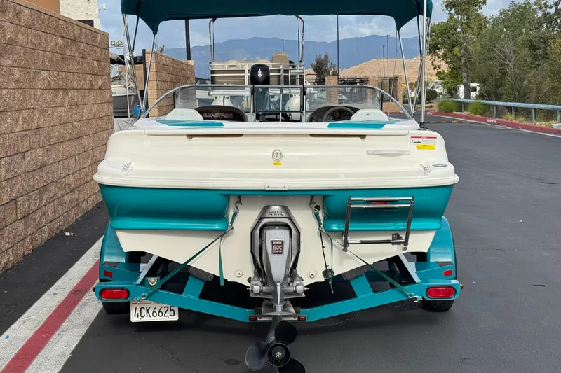 Slide: The Image of 1997 Glastron GS 185 boat on trailer, rear view, teal and white color scheme. - 4