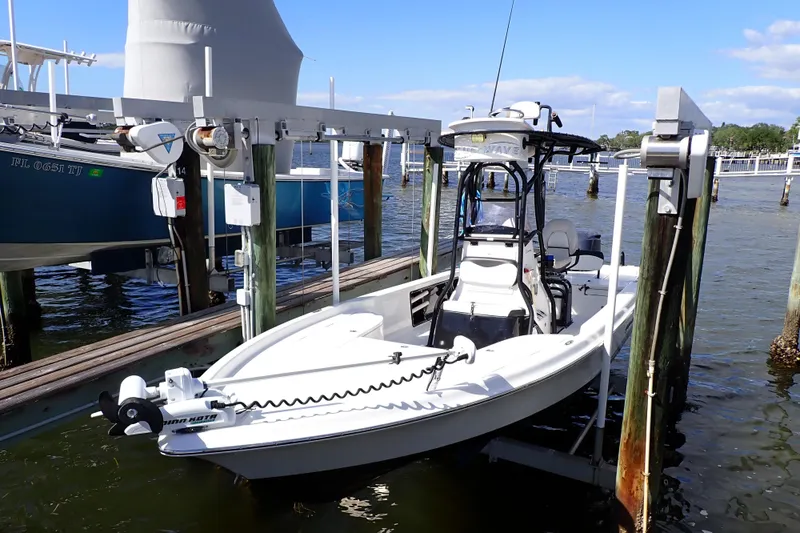 Slide: The Image of 2015 Blue Wave 2400 PureBay boat docked on a lift by the water. - 2