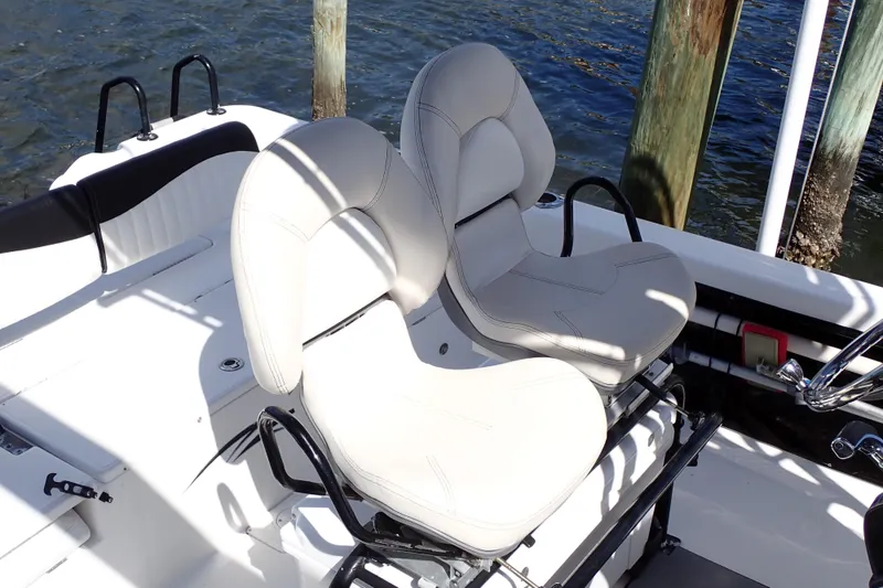 Slide: The Image of 2015 Blue Wave 2400 PureBay boat with dual white cushioned seats by the water. - 8