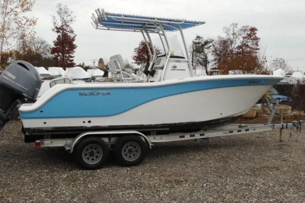 The Image of 2021 Sea Fox 228 Commander boat on trailer, blue and white design, parked outdoors. - 1