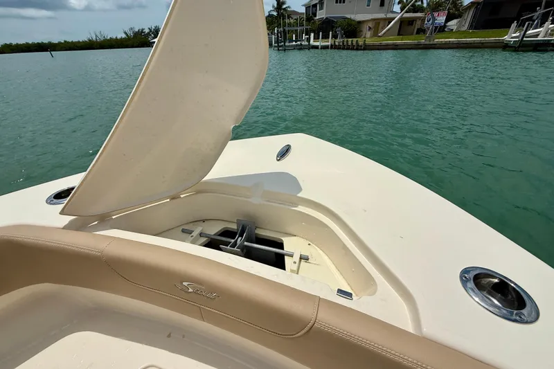 Slide: The Image of 2023 Scout 215 XSF boat with open storage compartment on calm water. - 10