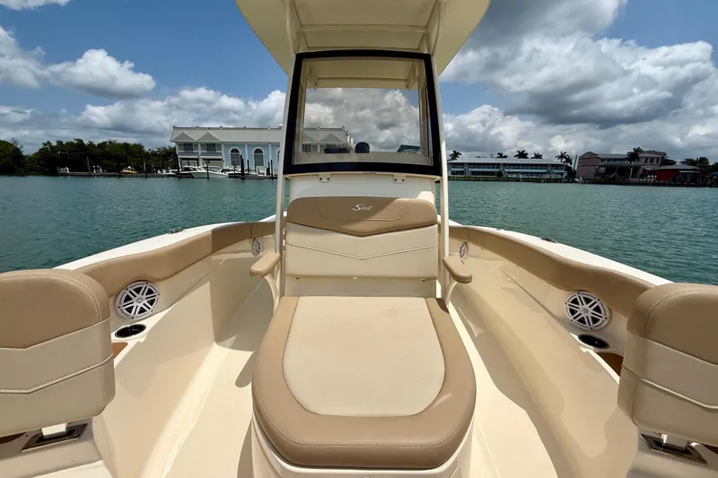Slide: The Image of 2023 Scout 215 XSF boat interior with beige seating, on a sunny waterfront. - 12