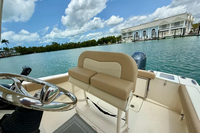 Slide: The Image of 2023 Scout 215 XSF boat interior with helm and seating, dockside view. - 15