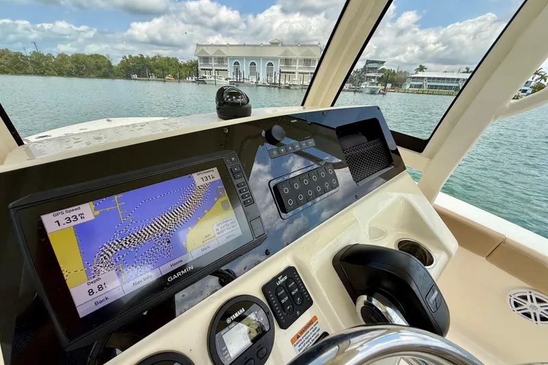 Slide: The Image of 2023 Scout 215 XSF boat dashboard with GPS navigation system on a scenic waterway. - 18