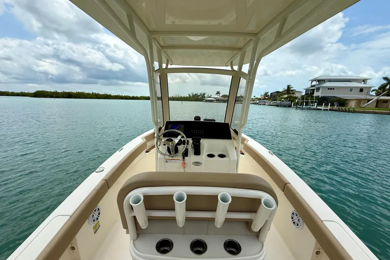 Slide: The Image of 2023 Scout 215 XSF boat on calm water, featuring a sleek helm and rod holders. - 19