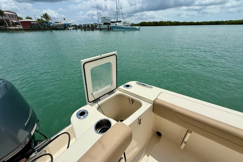 Slide: The Image of 2023 Scout 215 XSF boat interior with open hatch, docked near calm waters. - 22