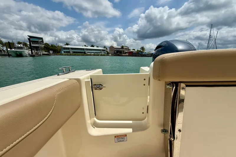 Slide: The Image of 2023 Scout 215 XSF boat interior with open door, overlooking marina and cloudy sky. - 24