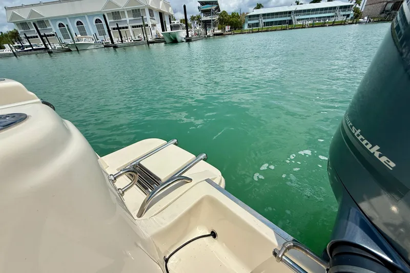 Slide: The Image of 2023 Scout 215 XSF boat with outboard motor on turquoise water near marina. - 27