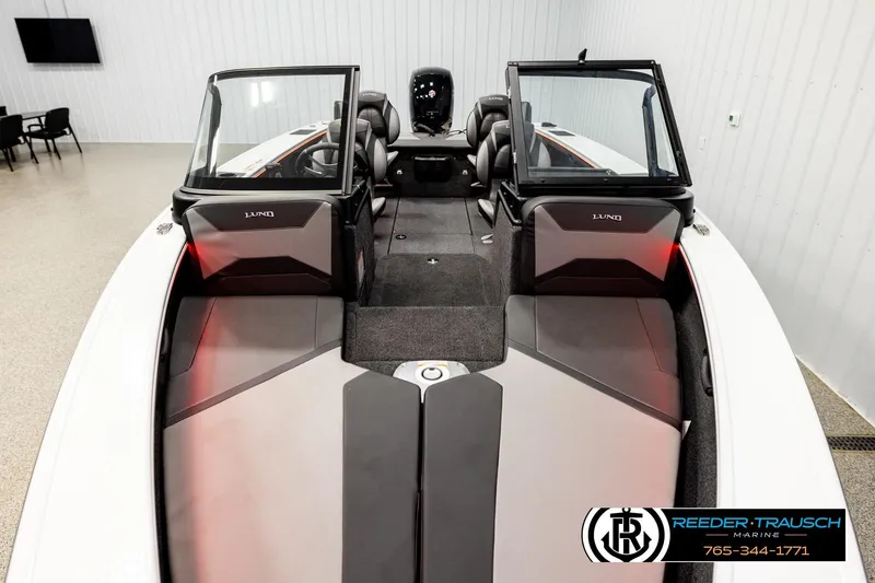 Slide: The Image of 2026 Lund 1875 Crossover XS boat interior with seating and windshield, displayed indoors. - 14
