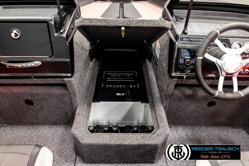 Slide: The Image of 2026 Lund 1875 Crossover XS boat interior with open storage compartment and steering wheel. - 23
