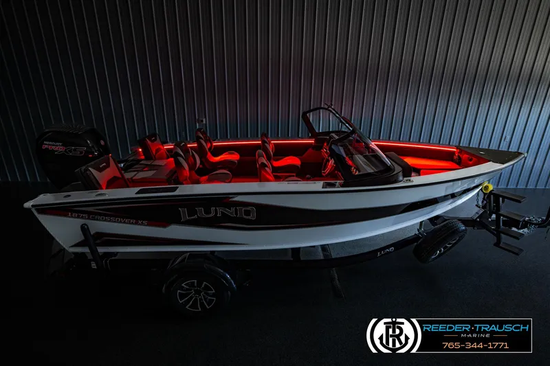 Slide: The Image of 2026 Lund 1875 Crossover XS boat with red interior lighting, displayed indoors. - 57