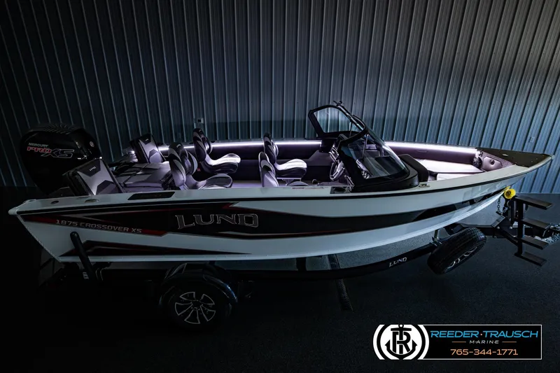 Slide: The Image of 2026 Lund 1875 Crossover XS boat in showroom, featuring sleek design and Mercury Pro XS engine. - 58
