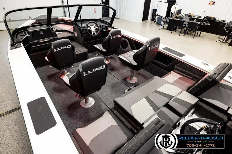Slide: The Image of 2026 Lund 1875 Crossover XS boat interior with seating and steering wheel in showroom. - 9