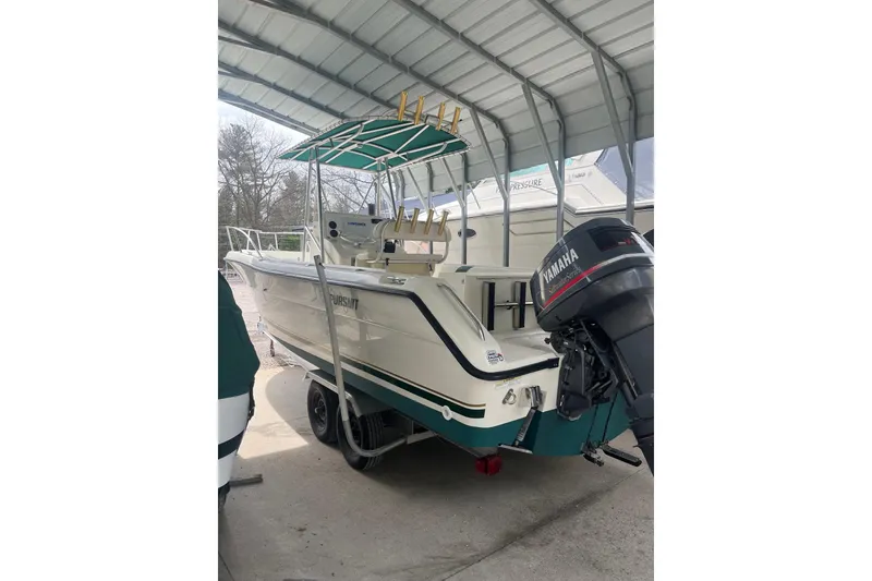 The Image of 1998 Pursuit 2470 Center Console boat with Yamaha outboard motor under a metal canopy. - 1