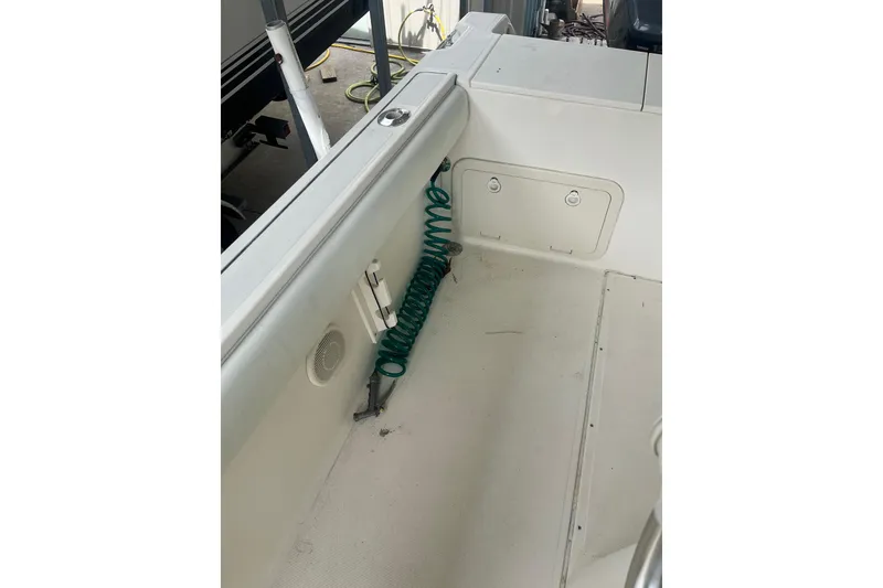 Slide: The Image of 1998 Pursuit 2470 Center Console boat interior with coiled green hose and storage compartments. - 8