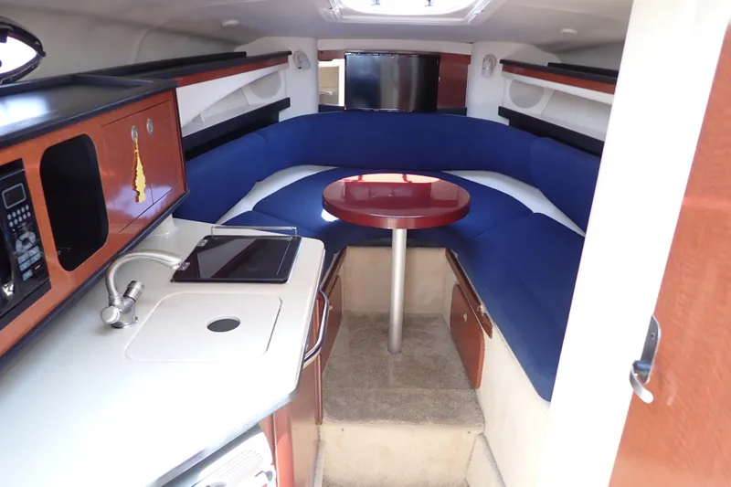 Slide: The Image of Interior of 2005 Sea Ray Sundancer 260 with blue seating and compact kitchenette. - 10