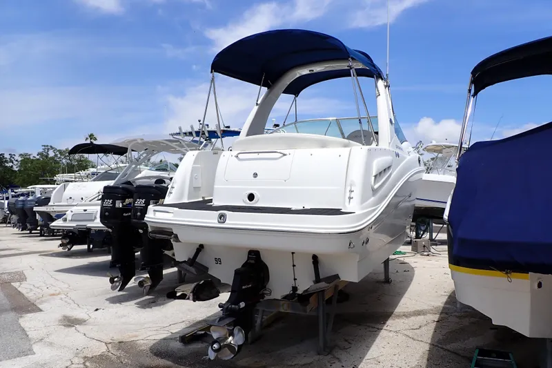 Slide: The Image of 2005 Sea Ray Sundancer 260 boat with blue canopy, docked outdoors under clear sky. - 136