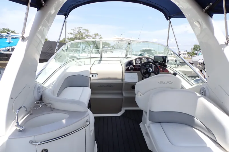 Slide: The Image of 2005 Sea Ray Sundancer 260 boat interior with helm, seating, and sink under blue canopy. - 3