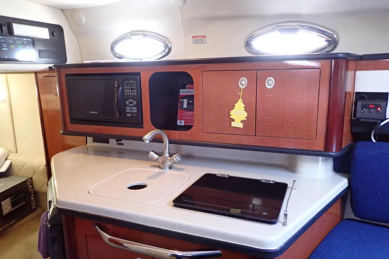 Slide: The Image of 2005 Sea Ray Sundancer 260 cabin kitchen with microwave, sink, and storage cabinets. - 55
