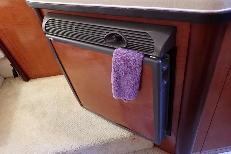 Slide: The Image of 2005 Sea Ray Sundancer 260 interior with a compact fridge and purple towel. - 62