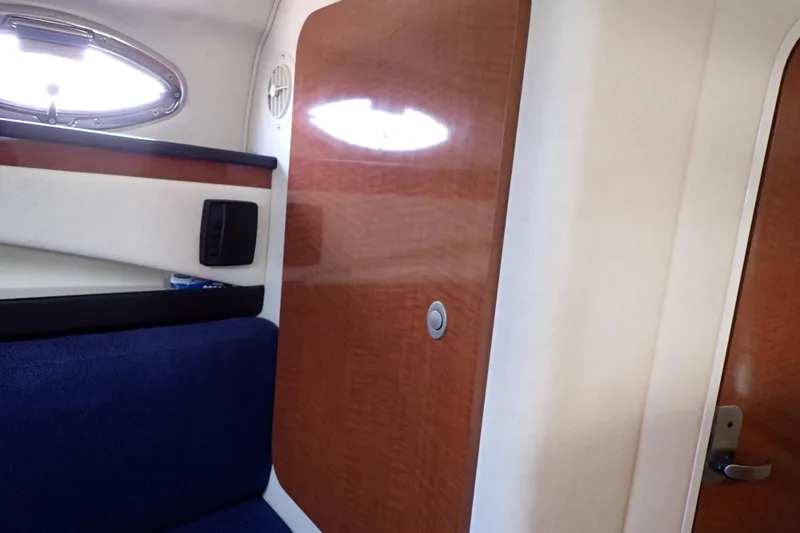 Slide: The Image of Interior cabin of 2005 Sea Ray Sundancer 260, featuring wood paneling and blue seating. - 76