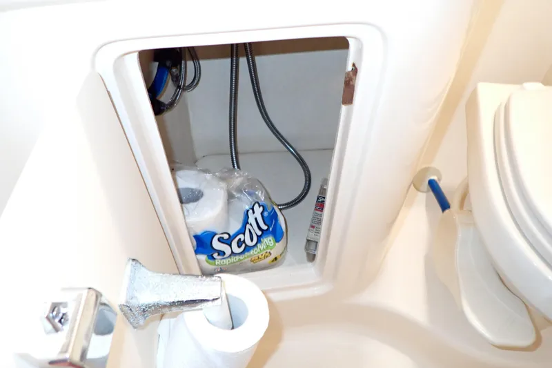 Slide: The Image of Storage compartment in 2005 Sea Ray Sundancer 260 boat bathroom with toilet paper and plumbing. - 85