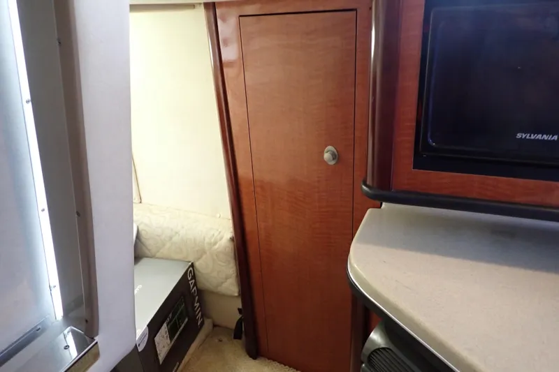 Slide: The Image of Interior of 2005 Sea Ray Sundancer 260, featuring wood cabinetry and compact living space. - 91
