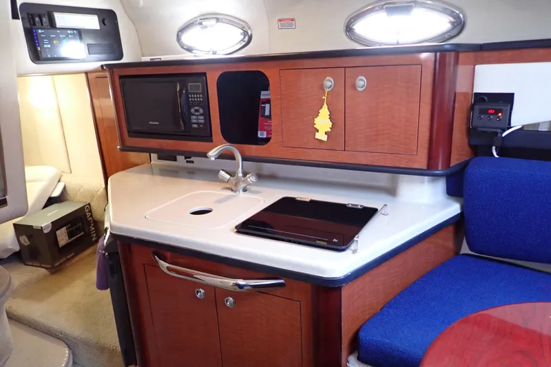 Slide: The Image of 2005 Sea Ray Sundancer 260 interior with kitchenette, featuring sink, microwave, and seating area. - 96