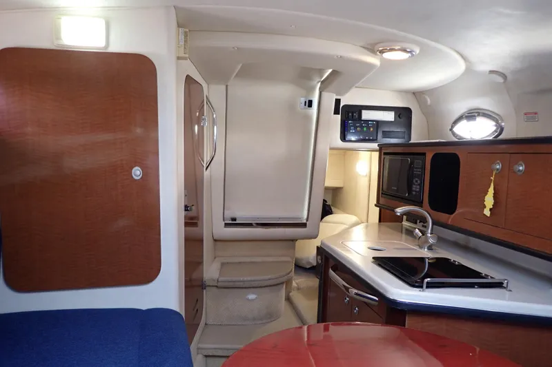 Slide: The Image of Interior of 2005 Sea Ray Sundancer 260, featuring kitchenette and cozy cabin space. - 97