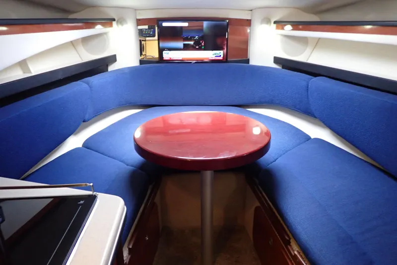Slide: The Image of Interior of 2005 Sea Ray Sundancer 260 with blue seating and wooden table. - 99