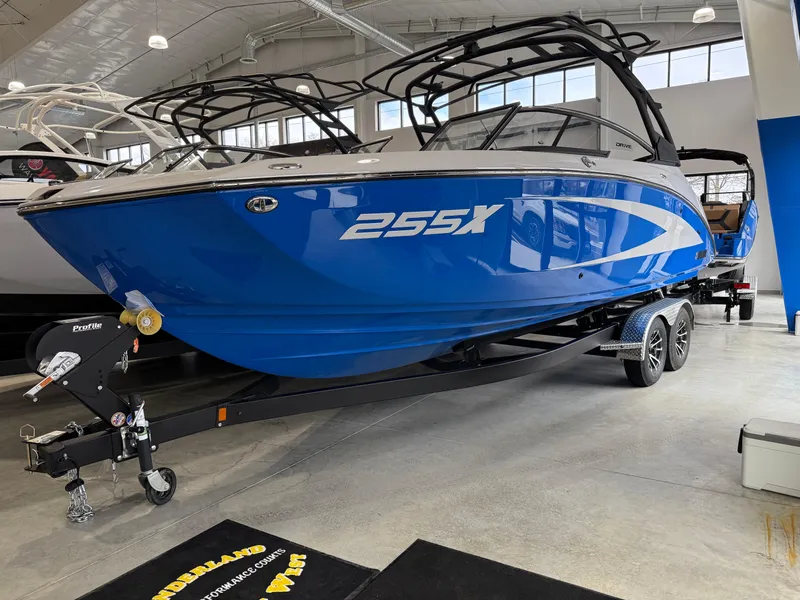 The Image of 2025 Yamaha Boats 255XD in showroom, vibrant blue hull, sleek design, on trailer. - 0