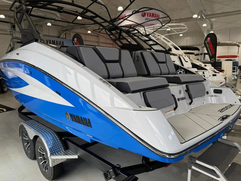 Slide: The Image of 2025 Yamaha Boats 255XD in showroom, featuring sleek blue and white design on trailer. - 2