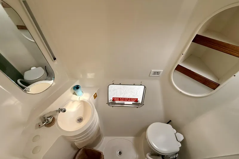 Slide: The Image of Bathroom interior of 1995 Fountaine Pajot Athena 38 catamaran, featuring sink, toilet, and storage shelves. - 27