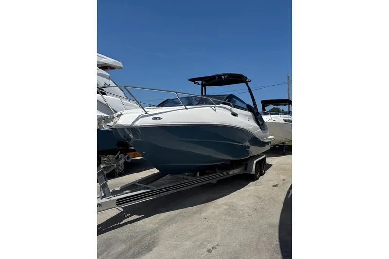 Slide: The Image of 2025 NX Boats NX270 on trailer, sleek design, parked outdoors under clear blue sky. - 13