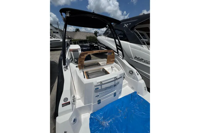 Slide: The Image of 2025 NX Boats NX270, sleek design, spacious deck, modern features, under a clear blue sky. - 14